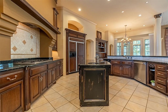 kitchen featuring light tile patterned floors, decorative backsplash, dark stone countertops, hanging light fixtures, and stainless steel appliances