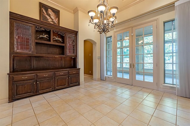 entryway featuring an inviting chandelier, arched walkways, crown molding, and light tile patterned flooring