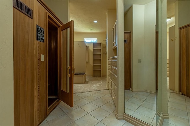 hall with light colored carpet, visible vents, and light tile patterned floors