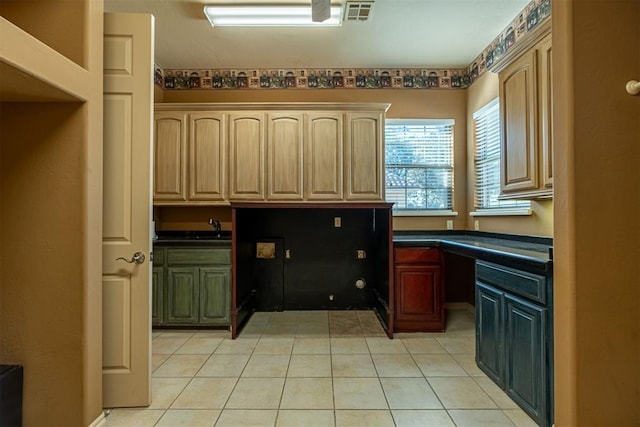 kitchen with dark countertops, light tile patterned floors, visible vents, and built in desk