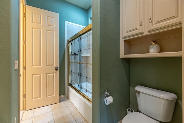 full bath with bath / shower combo with glass door, toilet, and tile patterned floors