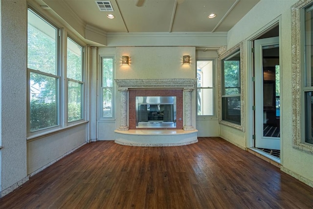 unfurnished living room featuring a healthy amount of sunlight, visible vents, wood finished floors, and a glass covered fireplace