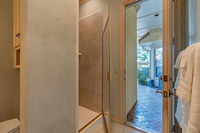 full bath with a textured wall, a stall shower, tile patterned flooring, and toilet