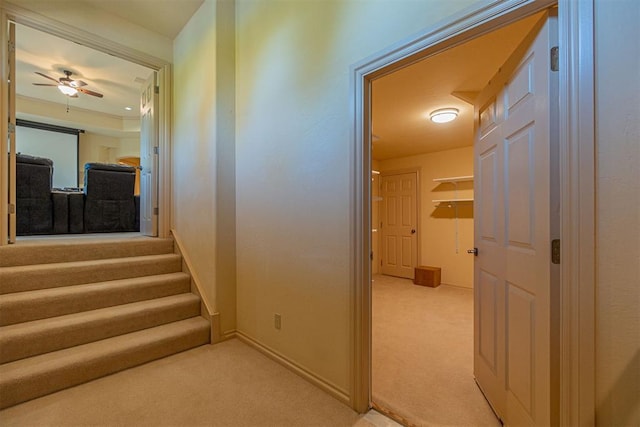 hallway with light carpet, stairway, and baseboards