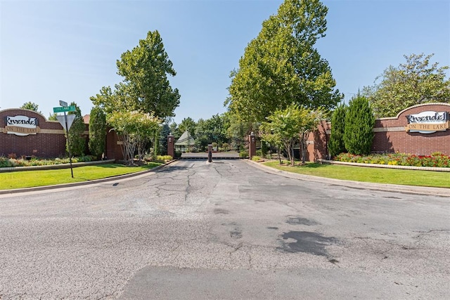 view of road with sidewalks, a gated entry, and curbs