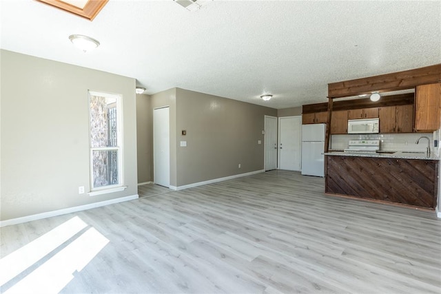 kitchen featuring a skylight, white appliances, and light wood-type flooring