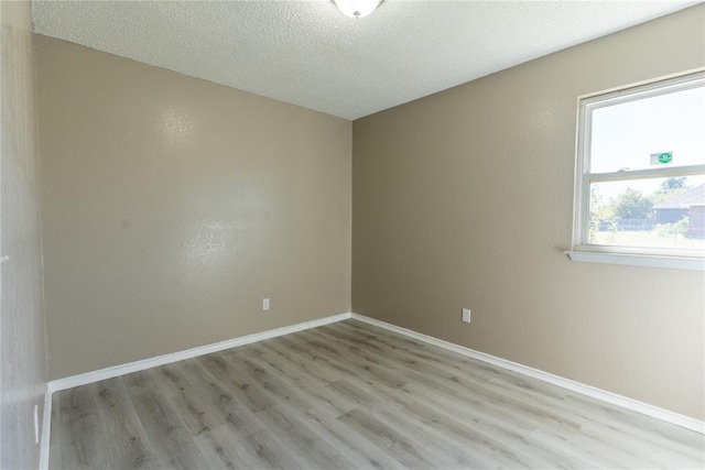 spare room with a textured ceiling and light hardwood / wood-style flooring