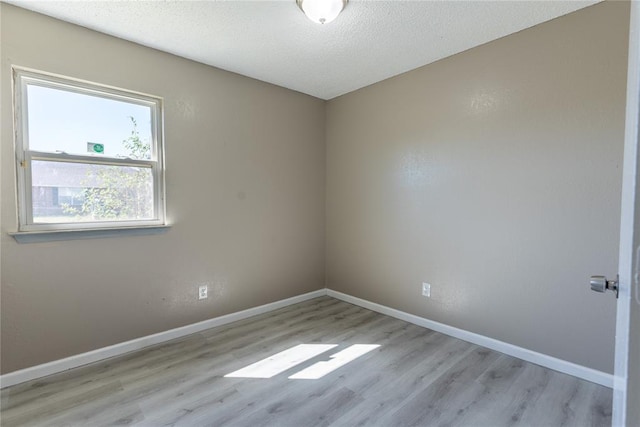 spare room with a textured ceiling and light hardwood / wood-style floors