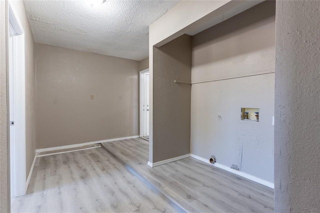 laundry room featuring electric dryer hookup, light wood-type flooring, a textured ceiling, and hookup for a washing machine