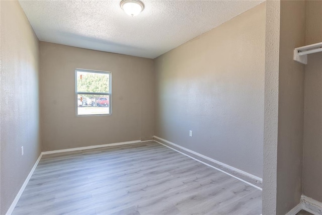 unfurnished room featuring a textured ceiling and light hardwood / wood-style floors