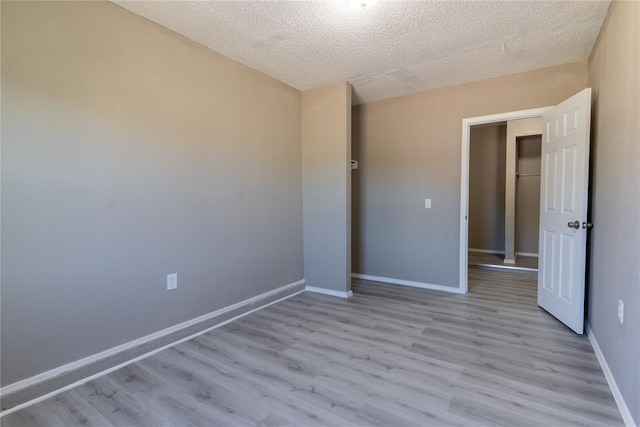 spare room with a textured ceiling and light hardwood / wood-style floors