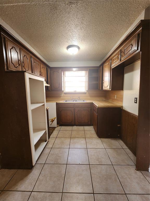 5300 Creekwood Ter, Oklahoma City, OK 73135 - kitchen featuring a textured ceiling, dark brown cabinets, light tile patterned flooring, and open shelves