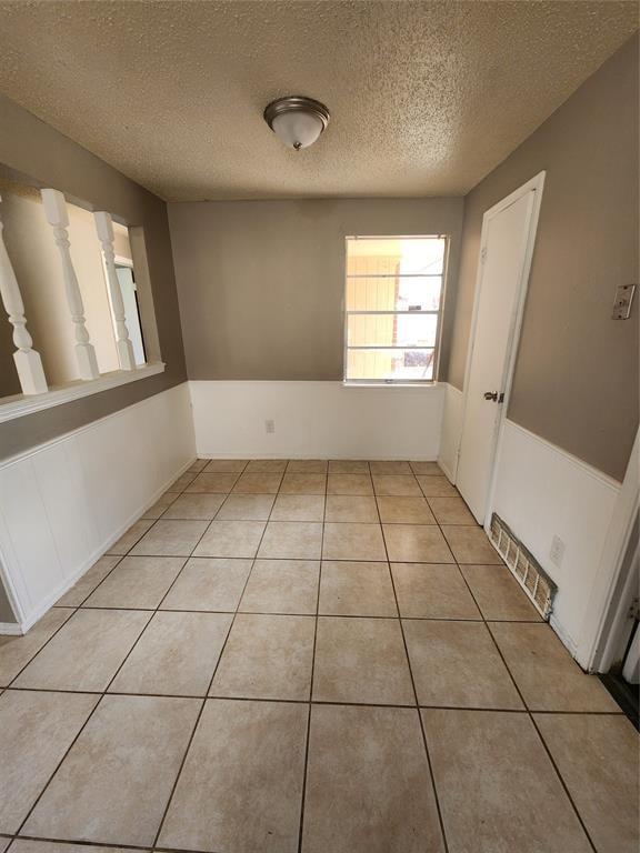 spare room featuring light tile patterned floors and a textured ceiling