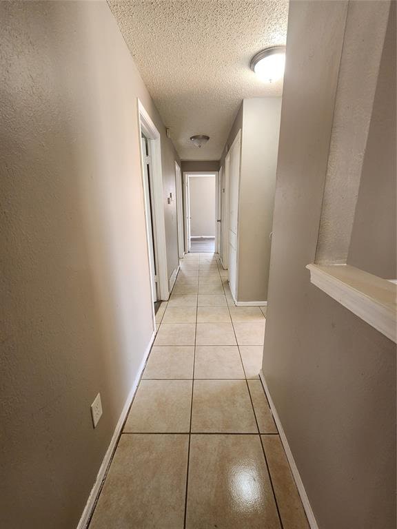 hall with light tile patterned floors and a textured ceiling