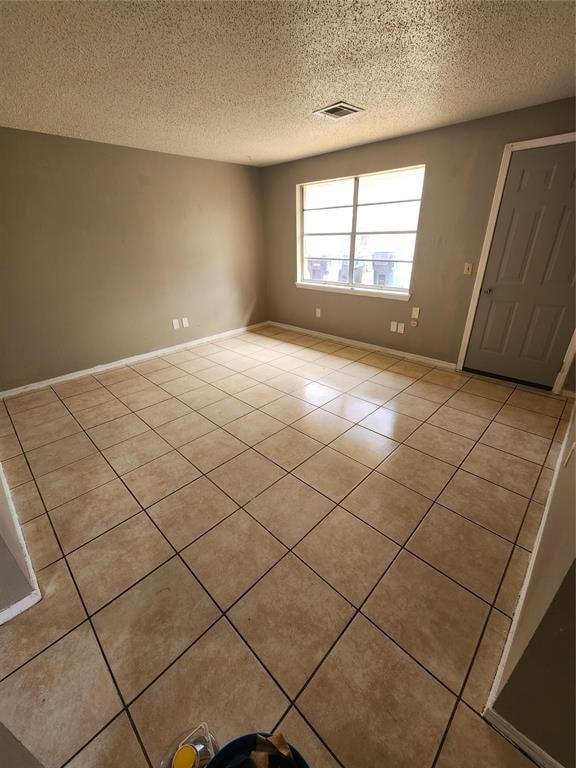 tiled spare room featuring a textured ceiling