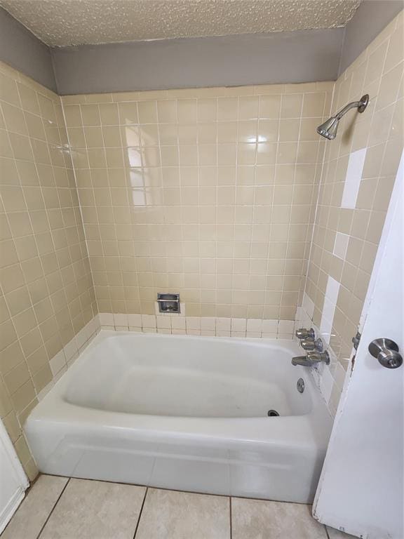 bathroom with tile patterned flooring, tiled shower / bath combo, and a textured ceiling