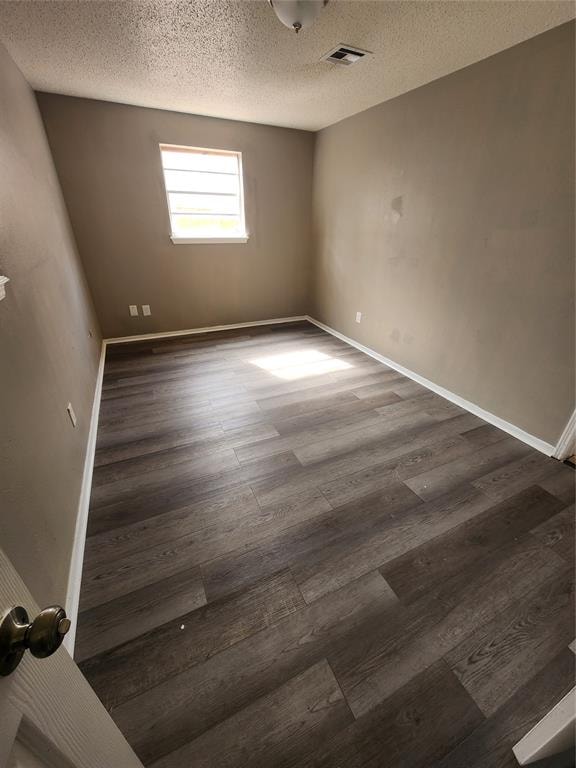 empty room featuring a textured ceiling and dark wood-type flooring