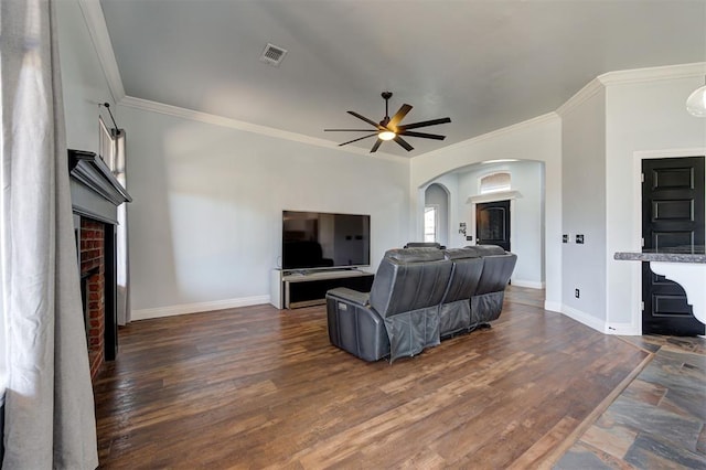 living room with a fireplace, crown molding, ceiling fan, and dark wood-type flooring