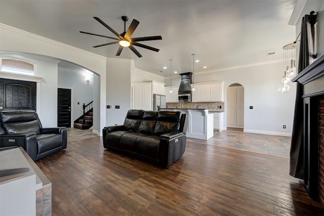 living room with crown molding, ceiling fan, and dark wood-type flooring