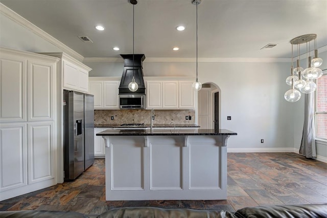 kitchen with a center island with sink, dark stone countertops, white cabinetry, and stainless steel appliances