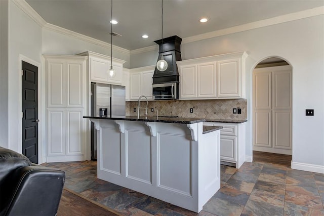 kitchen featuring appliances with stainless steel finishes, a center island with sink, white cabinetry, and dark stone counters