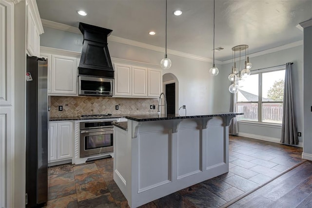 kitchen with appliances with stainless steel finishes, crown molding, white cabinets, dark hardwood / wood-style floors, and an island with sink