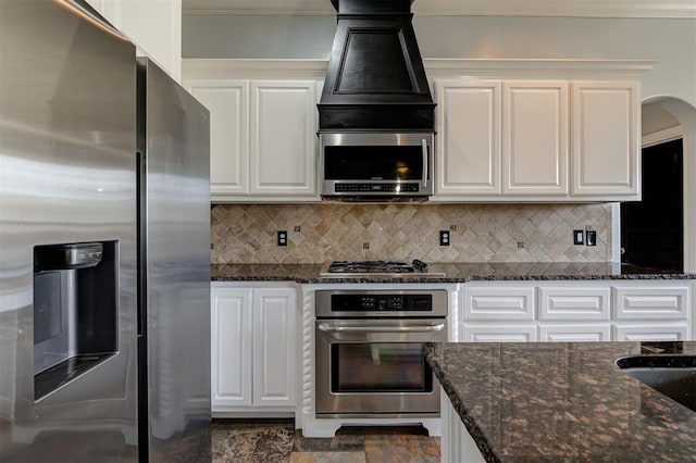 kitchen with white cabinets, appliances with stainless steel finishes, and dark stone countertops