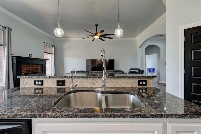 kitchen with ornamental molding, dark stone counters, ceiling fan, pendant lighting, and white cabinetry