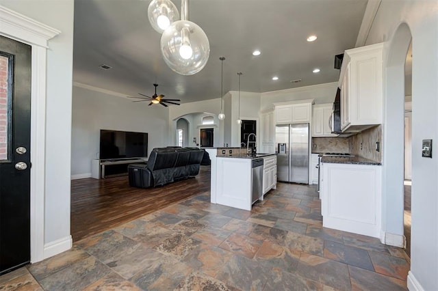 kitchen with appliances with stainless steel finishes, ceiling fan, pendant lighting, a center island with sink, and white cabinets