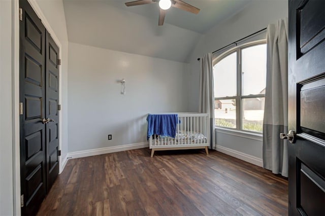 unfurnished bedroom featuring vaulted ceiling, a crib, ceiling fan, and dark hardwood / wood-style floors