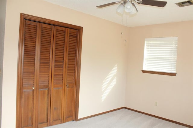 unfurnished bedroom featuring a closet, light colored carpet, and ceiling fan