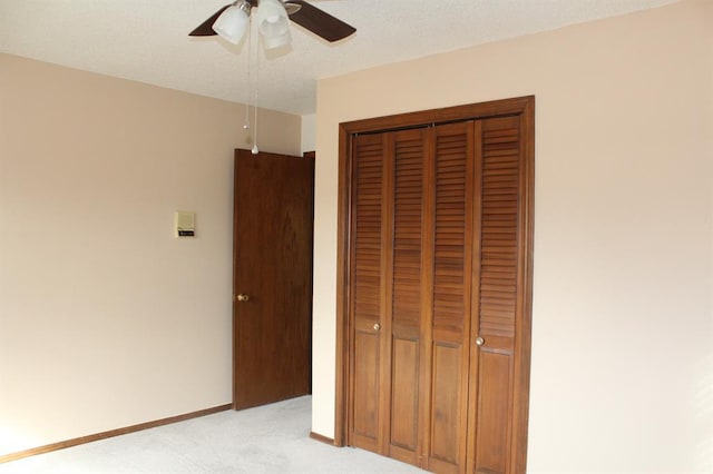 unfurnished bedroom with ceiling fan, light colored carpet, and a closet