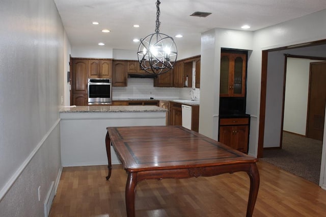 kitchen with decorative backsplash, wood-type flooring, white dishwasher, and hanging light fixtures