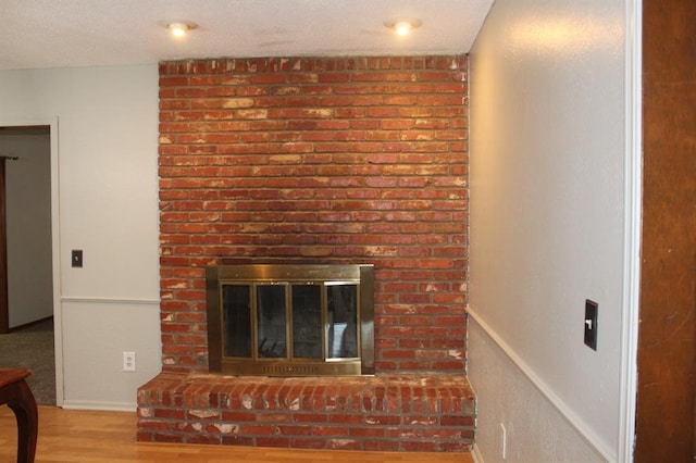 room details with hardwood / wood-style floors, a textured ceiling, and a brick fireplace