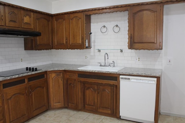 kitchen with tasteful backsplash, light stone counters, black electric cooktop, white dishwasher, and sink