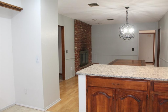 kitchen featuring a notable chandelier, decorative light fixtures, light hardwood / wood-style floors, and a brick fireplace