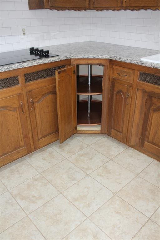 kitchen featuring black electric stovetop, light tile patterned floors, and backsplash