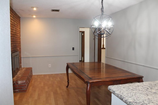 dining space featuring an inviting chandelier, light wood-type flooring, and a brick fireplace