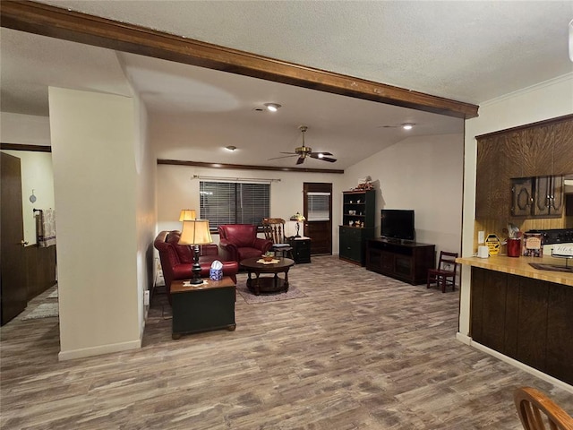 living room with hardwood / wood-style floors, ceiling fan, lofted ceiling with beams, and crown molding