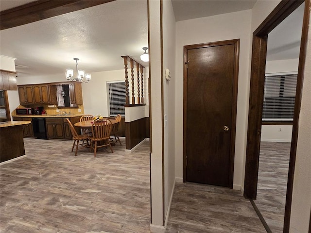 hall with sink, hardwood / wood-style floors, and an inviting chandelier