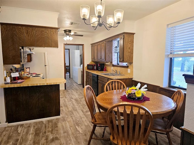 dining room featuring washer / dryer, crown molding, ceiling fan with notable chandelier, and light wood-type flooring