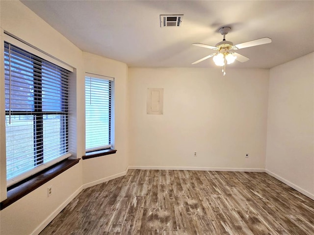 empty room with ceiling fan, dark hardwood / wood-style flooring, and electric panel