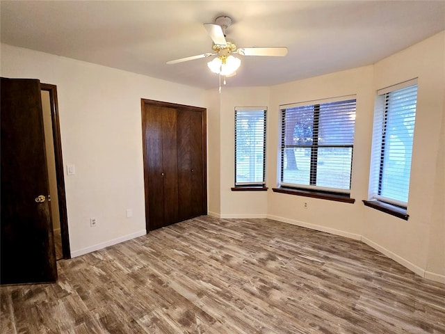 unfurnished bedroom with ceiling fan, a closet, and wood-type flooring