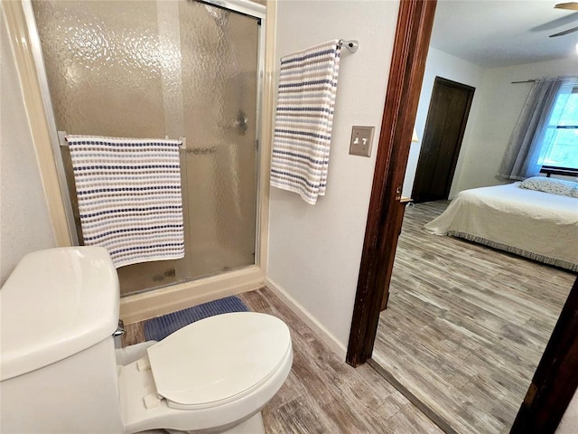 bathroom with hardwood / wood-style flooring, toilet, and a shower with shower door