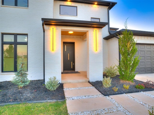 exterior entry at dusk featuring a garage