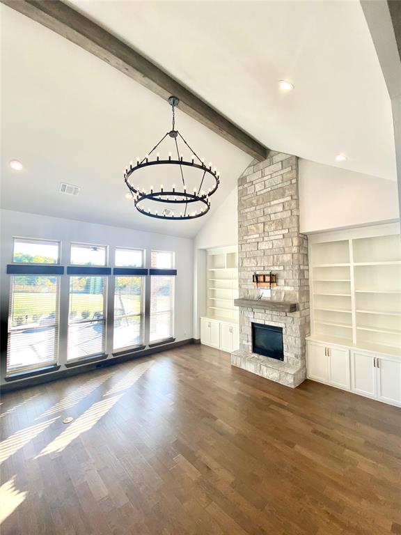 unfurnished living room featuring beamed ceiling, high vaulted ceiling, dark hardwood / wood-style floors, a chandelier, and a fireplace