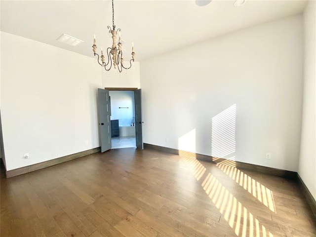 unfurnished room with wood-type flooring and an inviting chandelier