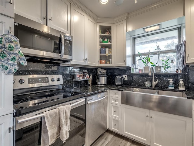 kitchen with white cabinets, appliances with stainless steel finishes, decorative backsplash, and dark stone counters