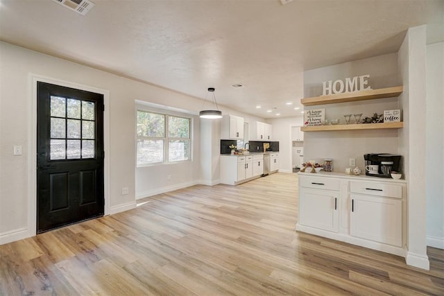 kitchen with decorative light fixtures, light wood-type flooring, and white cabinetry