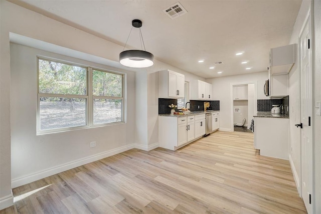 kitchen featuring dark stone countertops, white cabinetry, light hardwood / wood-style flooring, and tasteful backsplash